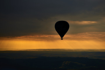 Aerial view of summer countryside during sunset with silhouette of hot air balloon