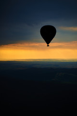 Aerial view of summer countryside during sunset with silhouette of hot air balloon