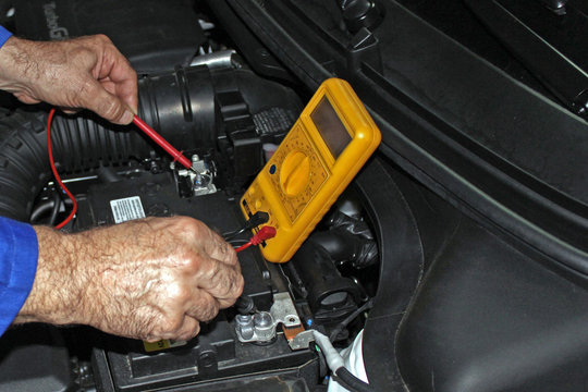 Mec&aacute;nico comprobando el voltaje de la bater&iacute;a del coche