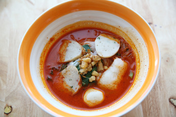 Fish and fishball Tom yum noodle on wood background , Thai food