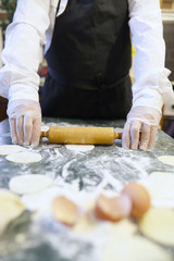 Male chef uses ingredients for preparing flour products on kitch