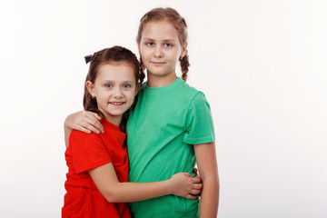 Two happy teenage girls hugging each other isolated on white background