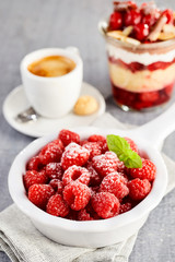 Bowl of fresh juicy raspberries against coffee