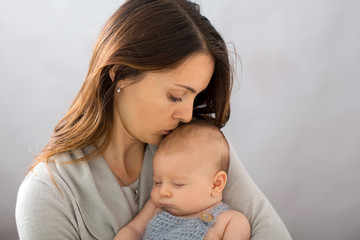 Young mother, caressing her newborn baby boy, holding him in her arms and smiling