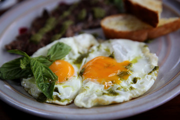 Grilled beef steak with toast , fried egg and vegetables on top with pesto sauce
