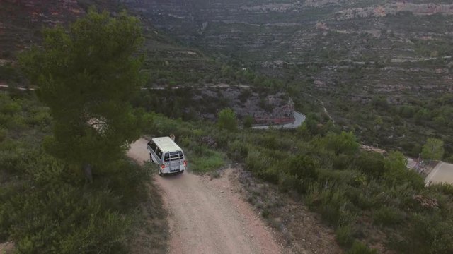 Epic astonishing drone footage from birds view on adventure exploring van or camper caravan riding through gravel off road forest trail high in mountains. concept nomad life