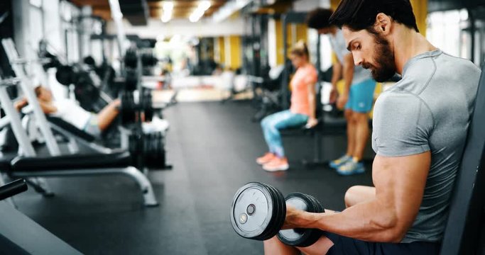 Young handsome man doing exercises in gym