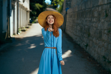 beautiful woman in a hat and in a blue dress shows a finger on a bruschatka