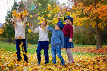 Group of small children in the park, having fun throwing leaves