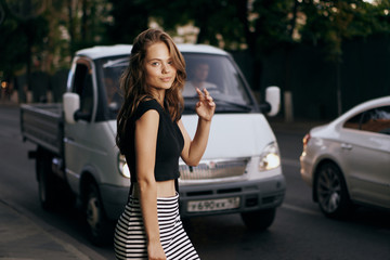 Friendly and beautiful girl on the street on the background of the car