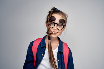 girl in glasses on a gray background with a pink backpack