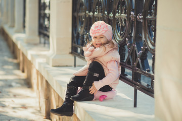 Dolly pin-up toothsome young girl wearing pinky jacket and warm winter hat fashion stylish clothes posing in autumn spring park weekend happyly smiling sitting on pathway track.