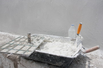 Fresh mortar in a container with trowels and other bricklayer tools