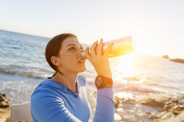 Woman drinking water on beach