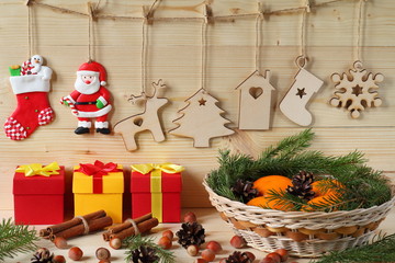 Christmas and New Year composition. Composition of Christmas and New Year decorations from plywood, a wicker basket with tangerines, color gift boxes, nuts and fir branches on a wooden background.