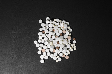Handful of pills on a black background closeup top view