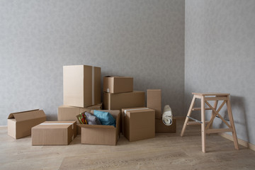 Cardboard boxes pile in new empty room with step-ladder