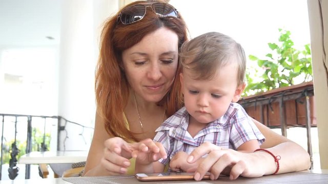 a little boy with mom uses the Internet on Smartphone
