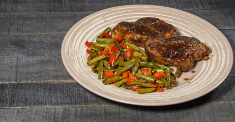Steamed steaks with beans and bell peppers on a plate top view