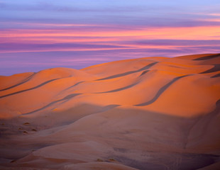 Sunset over sand dunes in desert abstract background