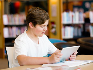 Teenage boy with tablet in library