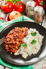 Hot chili con carne with ground beef, beans, tomatoes and corn served with rice
