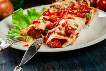 Traditional mexican enchiladas with chicken meat, spicy tomato sauce and cheese on a plate