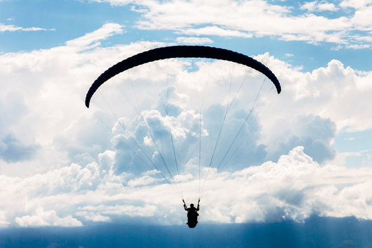 Paraglider silhouette on blue sky with clouds