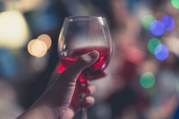 Handing holding a glass of wine on bokeh background