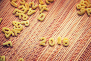 2018 written with alphabet pastas on wooden background