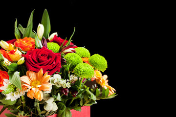 Bouquet of different flowers, roses, carnations, gerberas, sunflowers, irises, on a black background.
