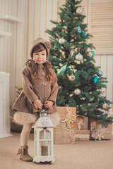 Young brunette dolly lady girl stylish dressed cozy warm winter gray jacket with fur posing sitting standing in studio close to Christmas New Year tree and presents.