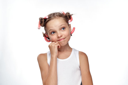 little girl in curlers in a white tank top on a light background