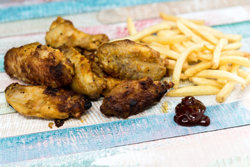 Chicken wings with sauce and golden French fries potatoes