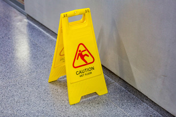 Yellow plastic warning wet floor sign standing on the ground
