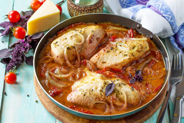 Baked chicken stuffed with tomatoes and cheese in a frying pan on the kitchen table.