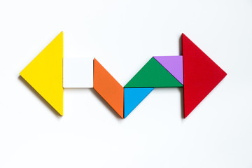 Color wood tangram puzzle on direction arrow shape in the opposite side on white background