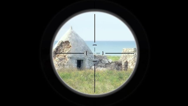 A sniper scope pointing at some typical Trullo houses in Apulia, Italy, near the sea, in the countryside.
