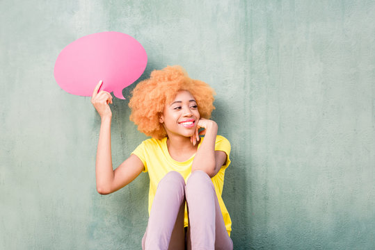 Beautiful african woman holding colorful thoughtful bubble on the green wall background
