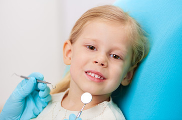 Pretty girl sitting on dentist chair checking up milk teeth. 