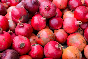 Close up bunch of fresh pomegranates on the farmer market. Pomegranate background. Organic, healthy, vegetarian diet food concept. Selective focus