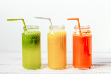 Fresh detox juices glass in row bottles on white background