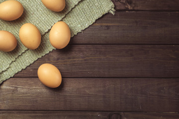 Chicken raw eggs on a dark wood background.