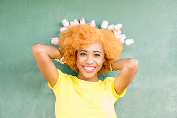 Colorful portrait of a beautiful african woman holding a bouquet of tulips on the green wall background