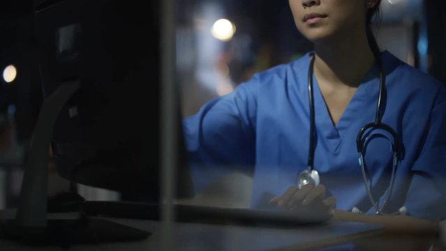  Close up hospital nurse on night shift working on computer