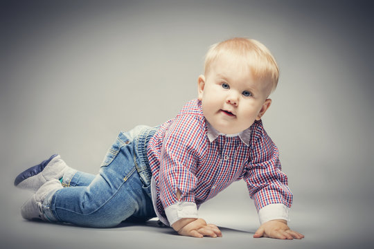 Little blond baby boy crawling on the ground.