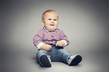 Naklejka premium Little child sitting on the floor, smiling.