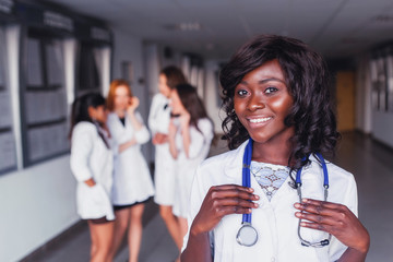 African American student medical worker, wearing a white coat, against the background of girlfriends with a beautiful smile. the future of healthcare 2018