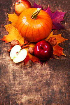 Autumn Pumpkin Thanksgiving Background with orange pumpkins, apples and fallen leaves on wooden table.
