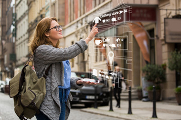 Augmented reality in marketing. Woman traveler with phone. Navigation on the projection of the display - obrazy, fototapety, plakaty